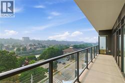 Spacious concrete balcony with glass and metal railing, offering expansive aerial perspectives of the surrounding urban landscape, trees, and waterway - 