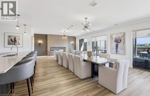 Open-concept common area featuring wood-finish flooring, a linear fireplace with a textured surround, and a large kitchen island with an undermount sink - 50 Grand Avenue S Unit# 713, Cambridge, ON - Indoor