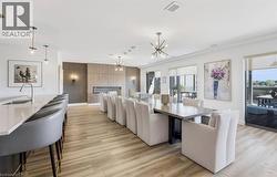 Open-concept common area featuring wood-finish flooring, a linear fireplace with a textured surround, and a large kitchen island with an undermount sink - 