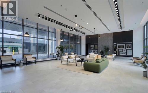 Spacious contemporary interior featuring floor-to-ceiling windows, light-toned tile flooring, recessed and track lighting, and a dark accent wall with patterned paneling - 50 Grand Avenue S Unit# 713, Cambridge, ON - Indoor Photo Showing Other Room