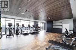 Fitness room featuring full-height windows, wood-finish flooring, and a paneled ceiling - 