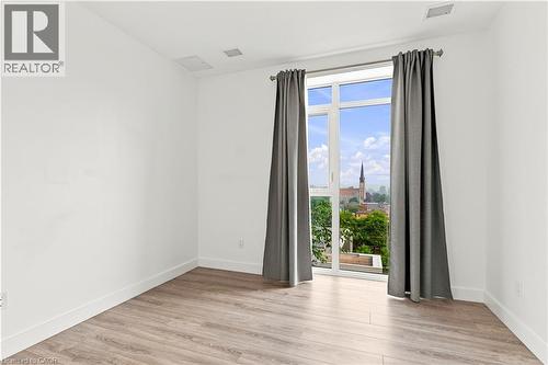 Bright room featuring a large window, wood-finish flooring, white baseboards, and neutral wall tones - 50 Grand Avenue S Unit# 713, Cambridge, ON - Indoor Photo Showing Other Room
