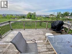 Spacious wood-finish deck with black metal spindle railing overlooking an expansive green space with mature trees - 