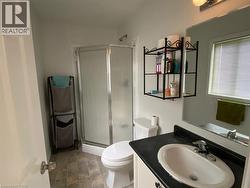 Bathroom featuring an enclosed shower, a single vanity with an integrated sink, a wall-mounted mirror, and a window with blinds - 