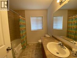 Bathroom featuring a vanity with an integrated sink, a large mirror, and overhead lighting - 