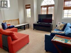 Open living area featuring neutral carpet flooring, an arched window, and additional windows with woven blinds - 