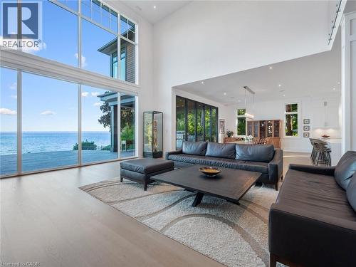 Expansive living area featuring soaring ceilings and panoramic water frontage through floor-to-ceiling windows - 140 Secord Lane, Burlington, ON - Indoor Photo Showing Living Room