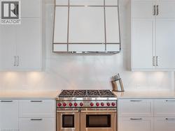 Professional-grade stainless steel range with red accents set against a white countertop and full-height backsplash - 