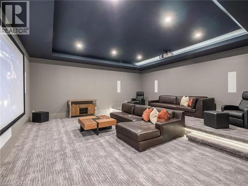 Dedicated media room featuring a large projection screen, recessed lighting, tiered seating platforms with integrated lighting, and patterned carpet flooring - 140 Secord Lane, Burlington, ON - Indoor