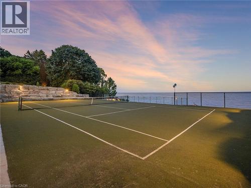 Tennis court featuring a synthetic grass surface, white court lines, and a black net - 140 Secord Lane, Burlington, ON - Outdoor With Body Of Water With View