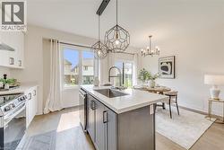 Kitchen with a central island featuring a stainless steel sink and matte black faucet, set against wood-finish flooring - 