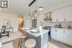 Contemporary kitchen featuring an island with seating, white shaker cabinetry, stainless steel appliances, and wood-finish flooring - 