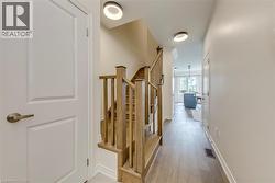 Hallway featuring wood-finish flooring, a wood staircase, recessed lighting, and a paneled door with bronze hardware - 