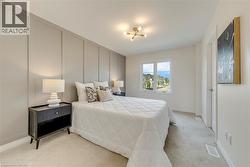 Bedroom featuring a board and batten accent wall, neutral carpeting, a large window, and an overhead light fixture - 