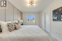 Bedroom featuring a paneled accent wall, a multi-bulb ceiling fixture, a window with exterior views, a white interior door, and light-colored carpeting - 