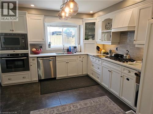 Kitchen with appliances with stainless steel finishes, light countertops, decorative backsplash, white cabinets, and recessed lighting - 20 Bird Court, Cambridge, ON - Indoor Photo Showing Kitchen With Double Sink
