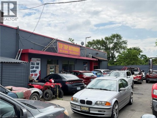 Commercial building with a grey brick facade and red trim, featuring a prominent red awning and a large sign - 350 Sherman Avenue N, Hamilton, ON 