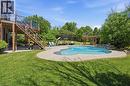 Freeform swimming pool with concrete surround, adjacent to a wooden deck with glass panel railings - 5779 Third Line, Guelph/Eramosa, ON  - Outdoor With In Ground Pool With Backyard 