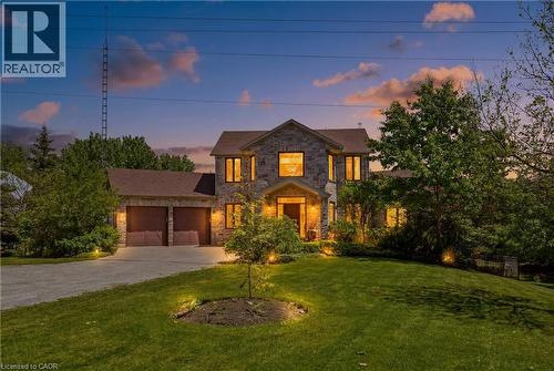 Stone facade residence featuring a two-car garage, mature landscaping, and an expansive front lawn - 5779 Third Line, Guelph/Eramosa, ON - Outdoor
