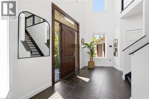Foyer featuring a dark wood-finish entry door with sidelights, dark tile flooring, a two-story ceiling, and a prominent staircase with dark handrails - 5779 Third Line, Guelph/Eramosa, ON - Indoor Photo Showing Other Room