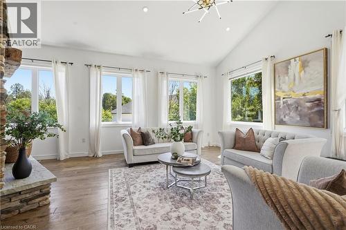 Vaulted ceiling living area featuring wood-finish flooring, a stone-clad fireplace, recessed lighting, and multiple windows - 5779 Third Line, Guelph/Eramosa, ON - Indoor Photo Showing Living Room
