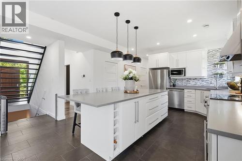 Modern kitchen featuring a large island with integrated storage, white cabinetry, stainless steel appliances, and a tiled backsplash - 5779 Third Line, Guelph/Eramosa, ON - Indoor Photo Showing Kitchen With Stainless Steel Kitchen With Upgraded Kitchen