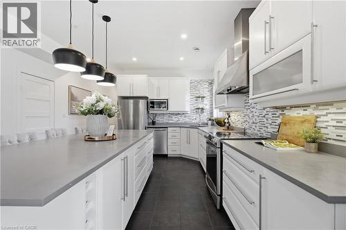 Contemporary kitchen featuring an expansive center island, white cabinetry with brushed nickel hardware, and dark tile flooring - 5779 Third Line, Guelph/Eramosa, ON - Indoor Photo Showing Kitchen With Stainless Steel Kitchen With Upgraded Kitchen