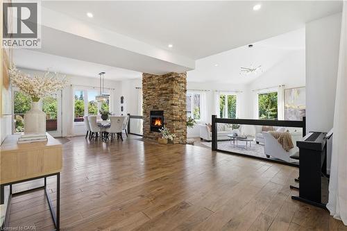 Spacious interior featuring wood-finish flooring, a stone-clad fireplace, vaulted ceilings, and recessed lighting - 5779 Third Line, Guelph/Eramosa, ON - Indoor Photo Showing Living Room