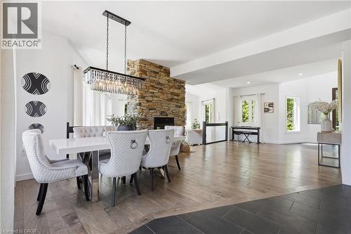 Open-concept living area featuring a stone-clad fireplace and a contemporary linear crystal chandelier - 5779 Third Line, Guelph/Eramosa, ON - Indoor Photo Showing Dining Room