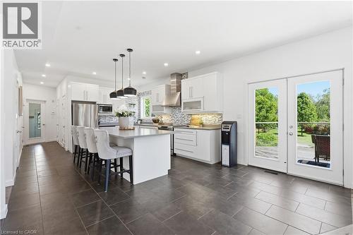 Open-concept kitchen featuring an island with pendant lighting, white cabinetry, stainless steel appliances, and a mosaic tile backsplash - 5779 Third Line, Guelph/Eramosa, ON - Indoor Photo Showing Kitchen With Stainless Steel Kitchen With Upgraded Kitchen