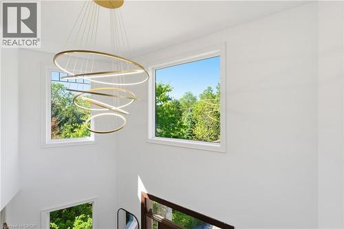 Modern multi-tier chandelier with ring lights, high ceilings, multiple windows, and a dark wood railing - 5779 Third Line, Guelph/Eramosa, ON - Indoor Photo Showing Other Room