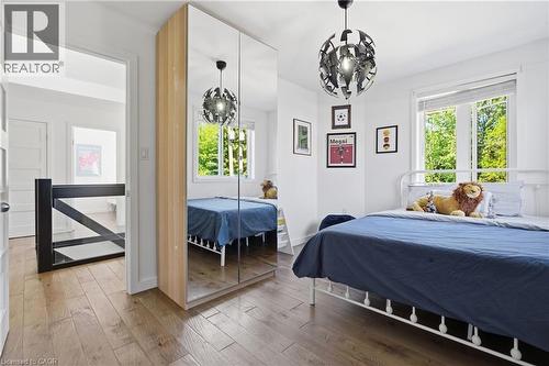 Bright interior space featuring wood-finish flooring, a contemporary ceiling light fixture, and a window with blinds - 5779 Third Line, Guelph/Eramosa, ON - Indoor Photo Showing Bedroom