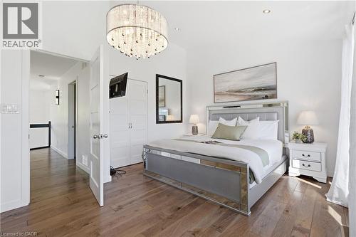 Spacious room featuring wood-finish flooring, a detailed crystal chandelier, and white paneled doors - 5779 Third Line, Guelph/Eramosa, ON - Indoor Photo Showing Bedroom