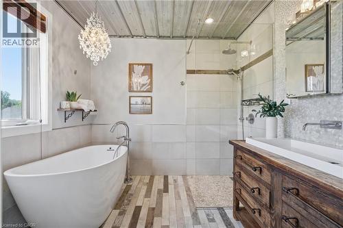 Bathroom featuring a freestanding soaking tub with a floor-mounted faucet, a walk-in shower with a glass enclosure and rain shower head, a wood-finish vanity with an integrated trough sink, and mosaic - 5779 Third Line, Guelph/Eramosa, ON - Indoor Photo Showing Bathroom