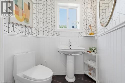 Powder room featuring a pedestal sink with chrome faucet, dark floor tiles, white wainscoting, and geometric pattern wallpaper - 5779 Third Line, Guelph/Eramosa, ON - Indoor Photo Showing Bathroom