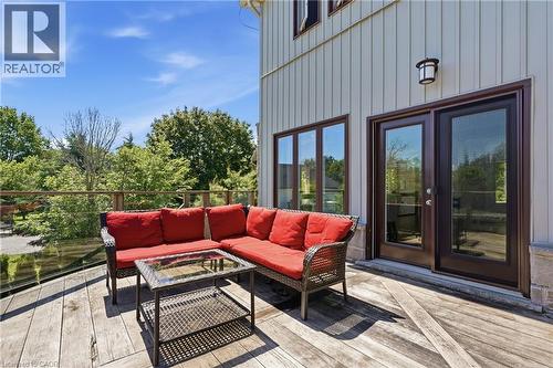 Expansive outdoor deck featuring weathered wood planks, a glass and wood railing, and direct access through a set of dark-framed glass doors - 5779 Third Line, Guelph/Eramosa, ON - Outdoor With Deck Patio Veranda With Exterior