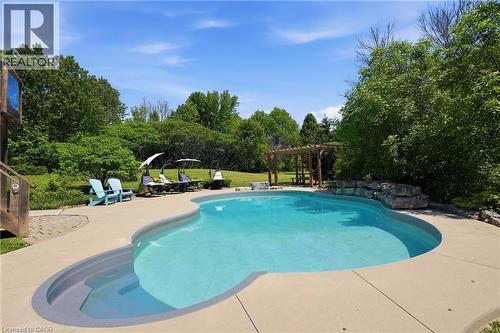 Curved swimming pool with integrated steps, surrounded by concrete decking - 5779 Third Line, Guelph/Eramosa, ON - Outdoor With In Ground Pool With Backyard