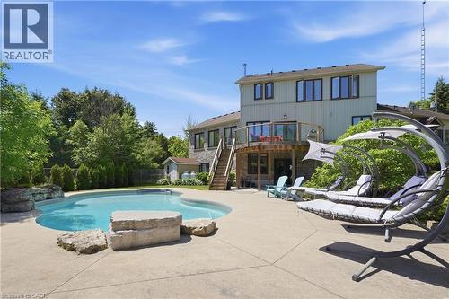 Irregularly shaped swimming pool with a concrete surround, rock features, and a stone retaining wall - 5779 Third Line, Guelph/Eramosa, ON - Outdoor With In Ground Pool With Backyard
