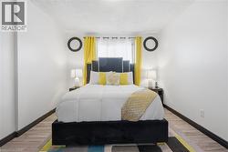 Bedroom featuring wood-finish flooring and a window with sheer and blackout curtains - 