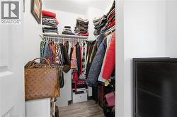 Walk-in closet featuring white walls, wood-finish flooring, built-in shelving, and hanging rods - 