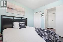 Bedroom featuring light blue walls, two white bi-fold closet doors, a dark wood-finish headboard, and wood-finish flooring visible in the doorway - 
