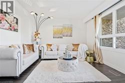 Bright living space featuring dark wood-finish flooring and a large window with white trim - 