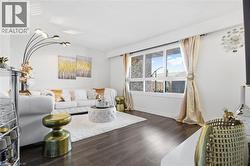 Living area featuring wood-finish flooring, white walls, and a large multi-pane window - 