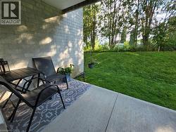 Concrete patio bordered by a block wall exterior, featuring a sloped lawn and mature trees - 