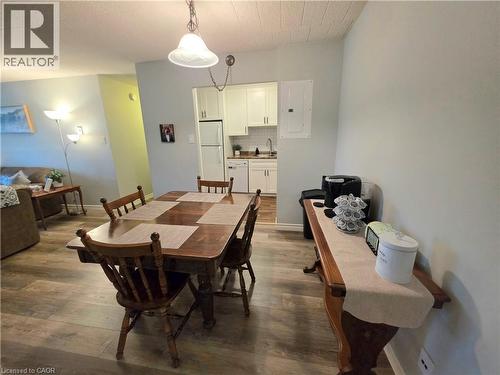Open-concept living space with wood-finish flooring, a dining area, and a kitchen featuring white cabinetry and subway tile backsplash - 24 Mooregate Crescent Unit# 103, Kitchener, ON - Indoor Photo Showing Dining Room