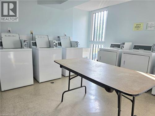 On-site laundry room with multiple top-load washing machines and front-load dryers - 24 Mooregate Crescent Unit# 103, Kitchener, ON - Indoor Photo Showing Laundry Room