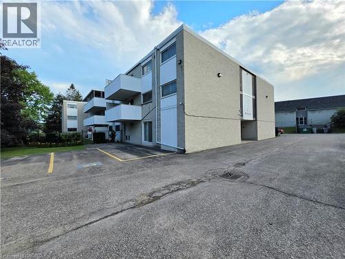 Contemporary apartment building featuring light gray brick exterior with white balcony railings - 24 Mooregate Crescent Unit# 103, Kitchener, ON - Outdoor