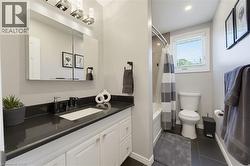 Bathroom featuring a white vanity with built-in sink, dark countertop, and large mirrored medicine cabinet - 