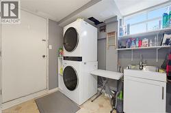 Dedicated laundry area featuring a stacked washer and dryer, a utility sink with a cabinet, and overhead shelving - 