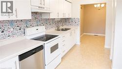 Kitchen featuring white cabinetry, light-toned countertops, a stainless steel dishwasher, and a double basin sink - 